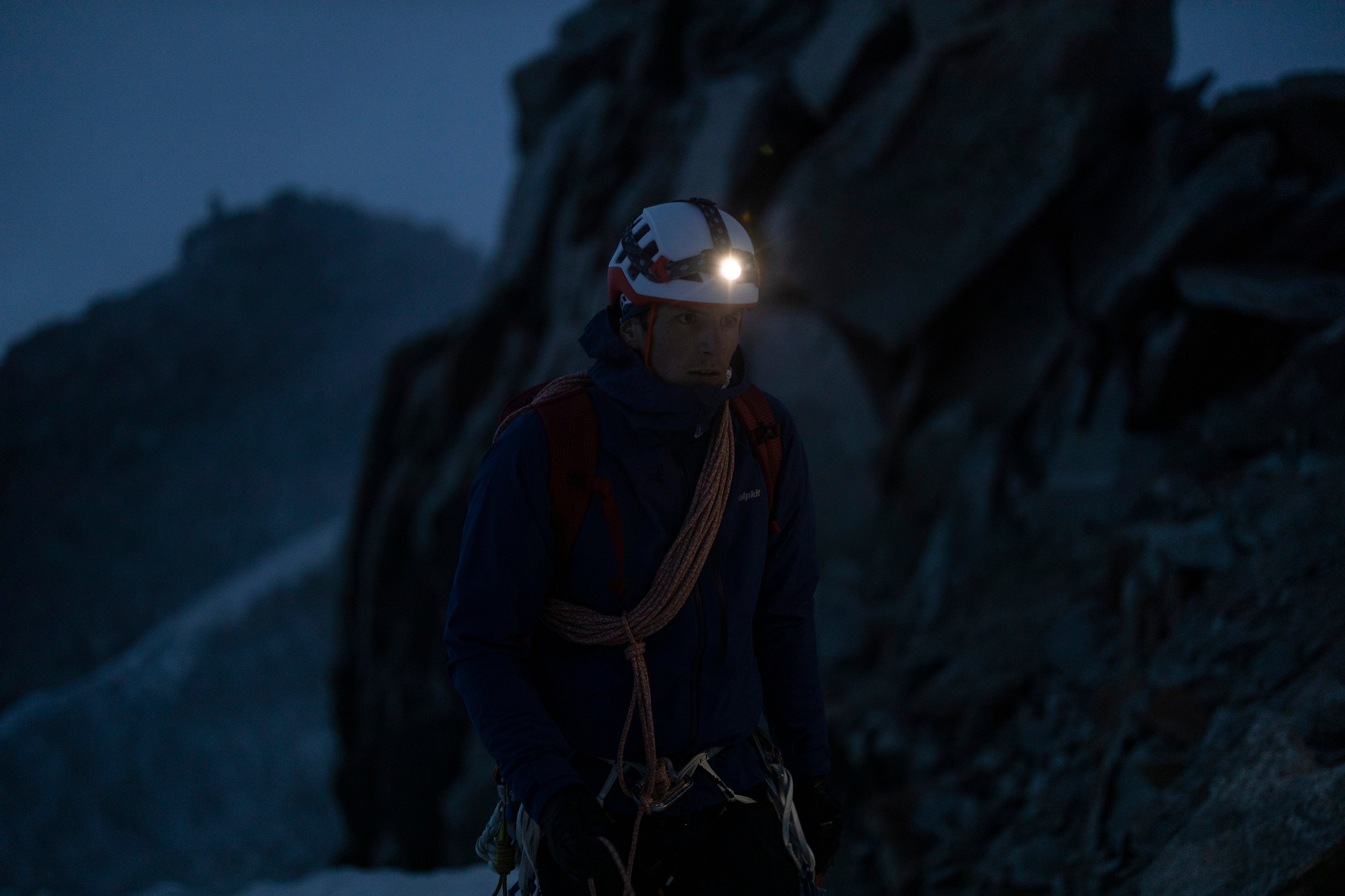 A man with a headtorch strapped over his climbing helmet