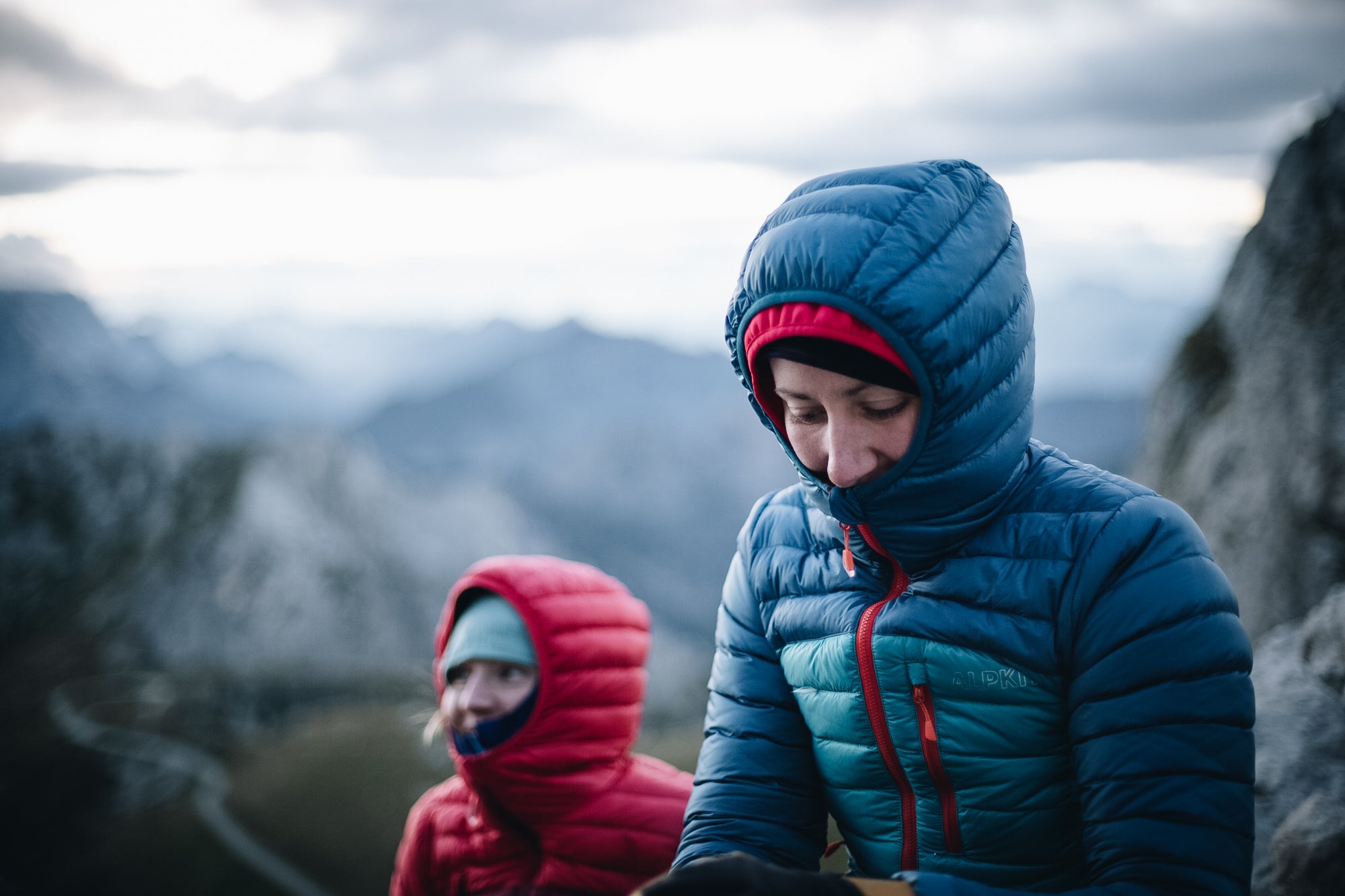 Two people sitting in the Slovenian Alps in ultralight Filament down jackets with the hoods up