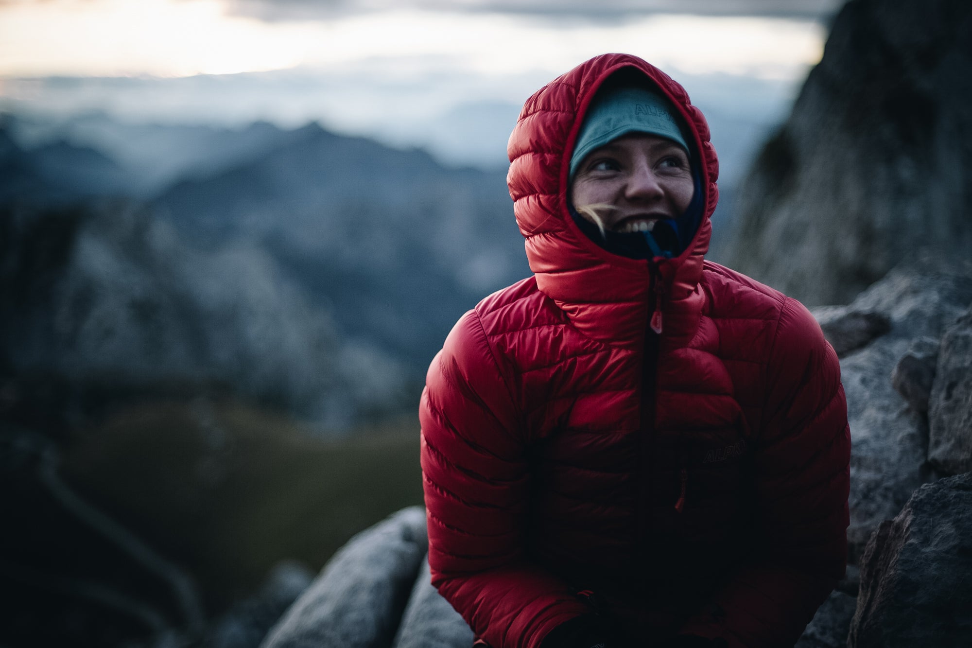 A woman wearing a Filament down jacket with the hood up in the Slovenian Alps