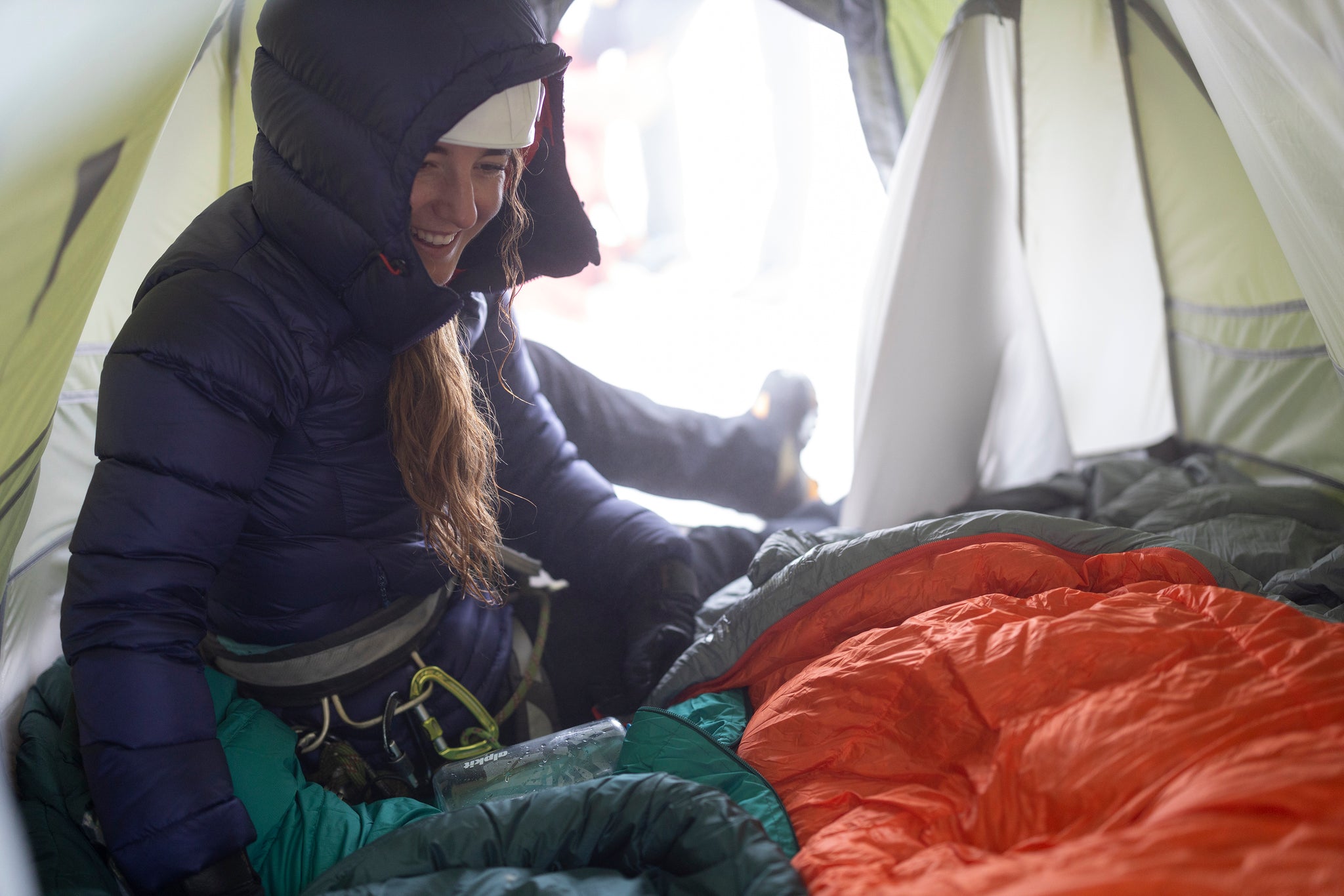 A woman inside the Kangri mountain tent in a Fantom hydrophobic down jacket with the AlpineDream 750FP goose down sleeping bag