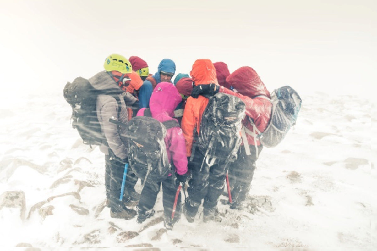 Hikers huddling together during stormy winter conditions