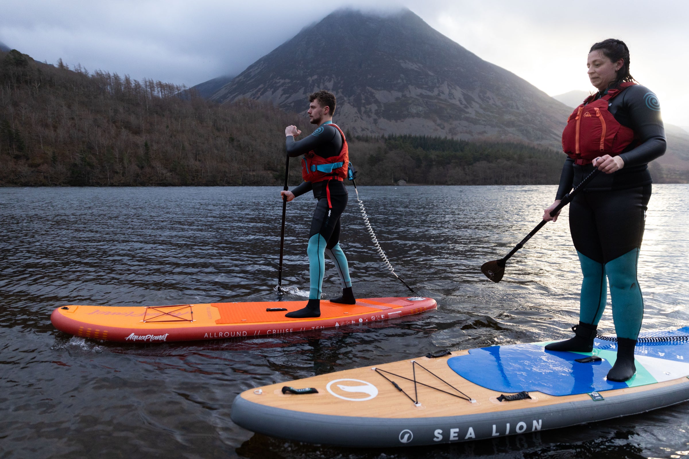 Two paddle boarders dressed in paddle boarding wetsuits