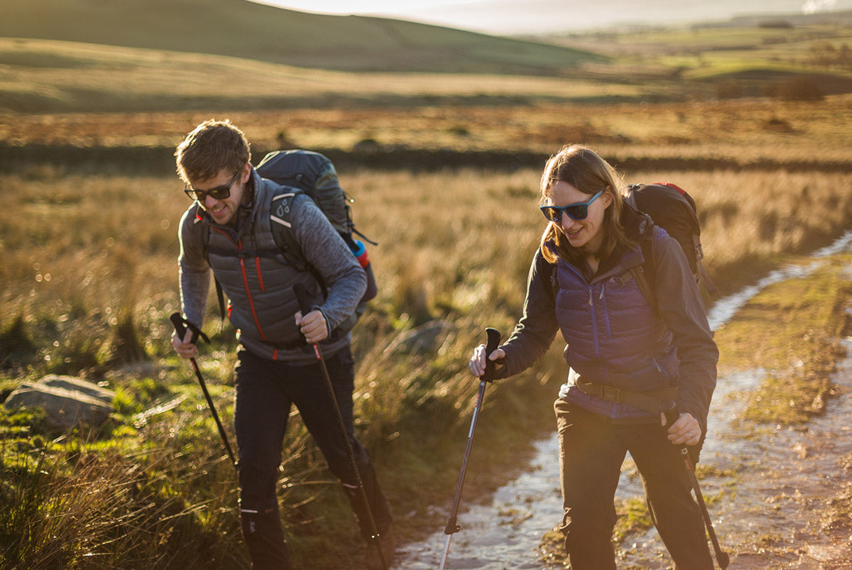 Two backpackers walking along a peak district path assisted with trekking poles