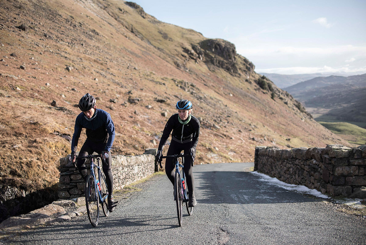 Two road cyclists climbing steep road in the Lake District