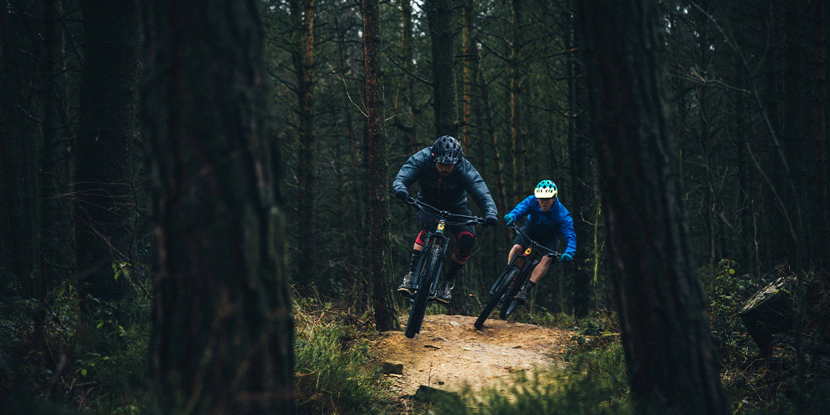 Two people mountain biking through the forest