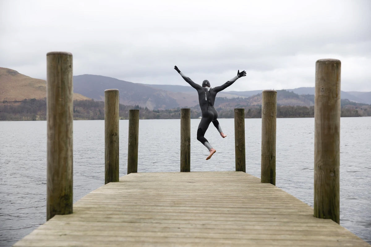 Wild swimmer in swimming wetsuits dives into a lake