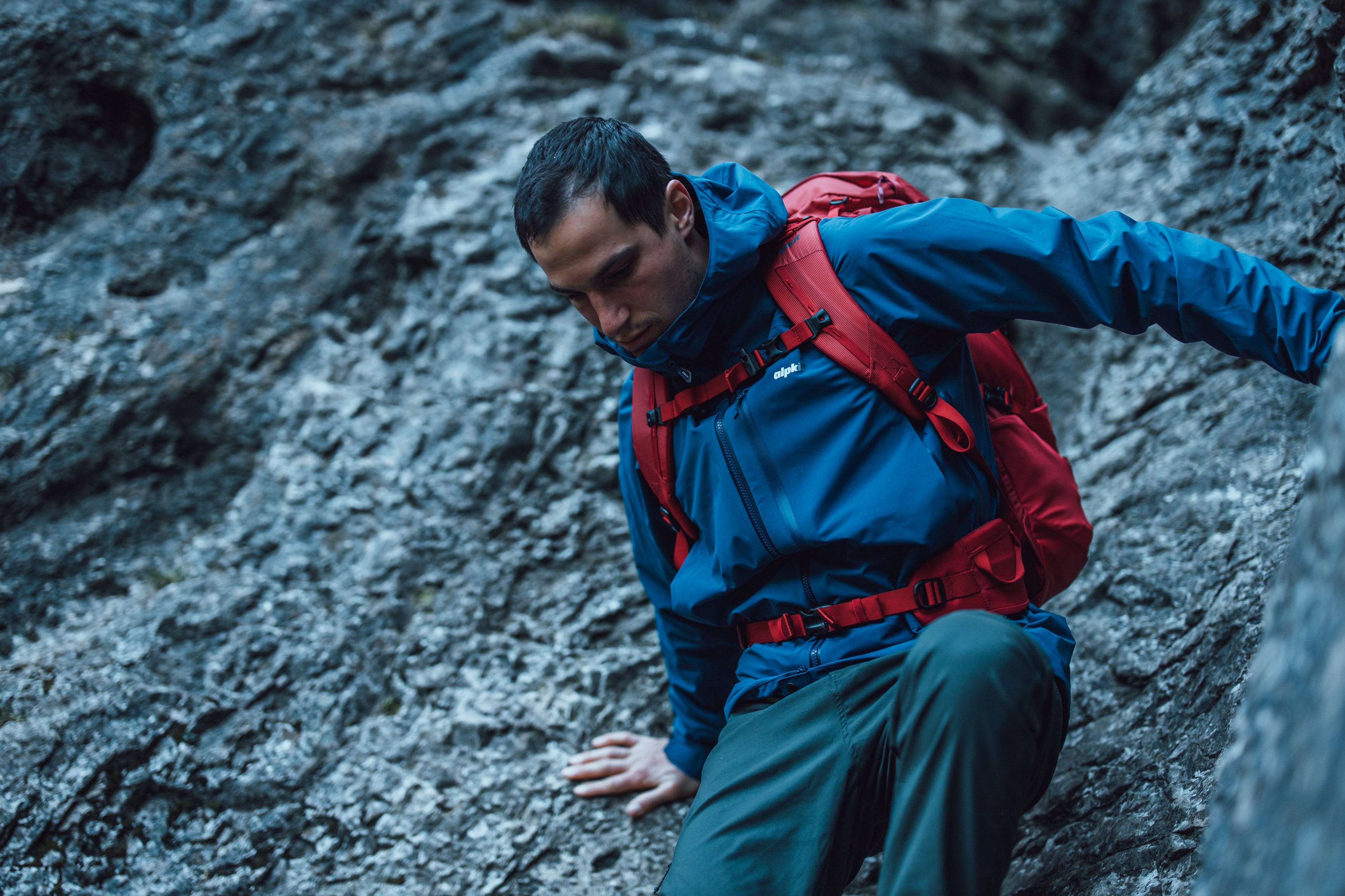 A man scrambling in the Alpkit Definition PFC-free technical mountaineering waterproof