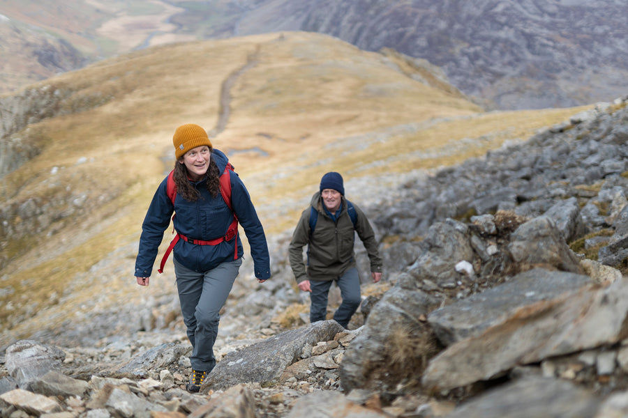 A woman and a man walking up Glyder Fawr and Glyder Fach in Snowdonia wearing organic Ventile jackets