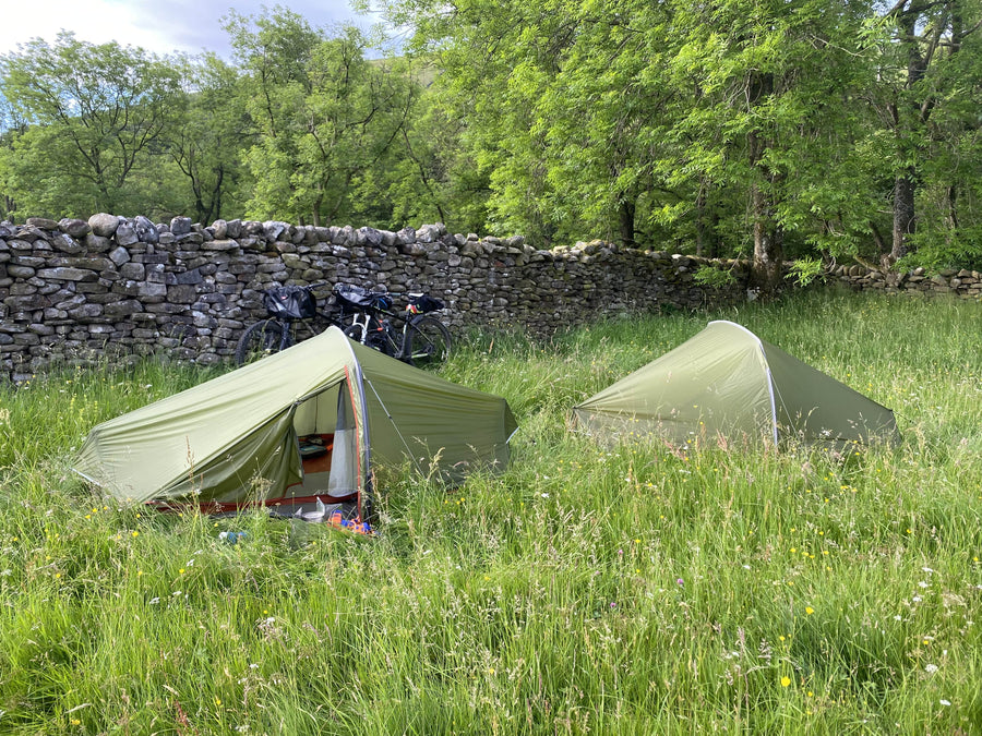 Lightweight hooped bivvy tents camped out behind wall