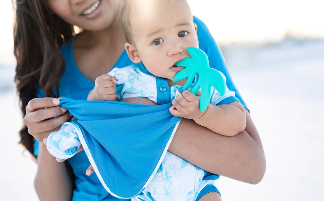 Woman holding a baby with our tie dye lovey and blue palm tree