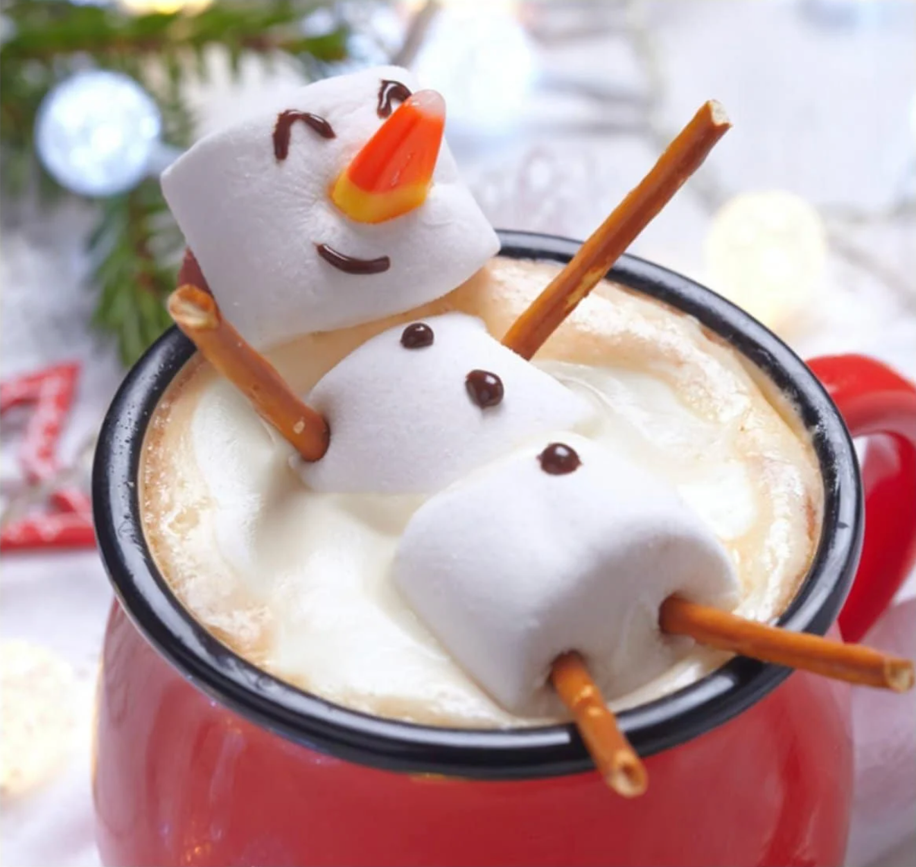 A snowman made out of marshmallows, sitting in a cup of hot chocolate.