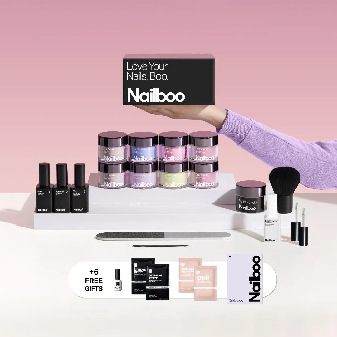 'Nailboo nail kit with powders, liquids, tools, and additional gifts on a pink background.'