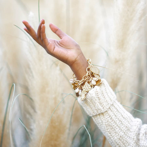 Image of hand in wheat field with bittersweet bracelets on. 