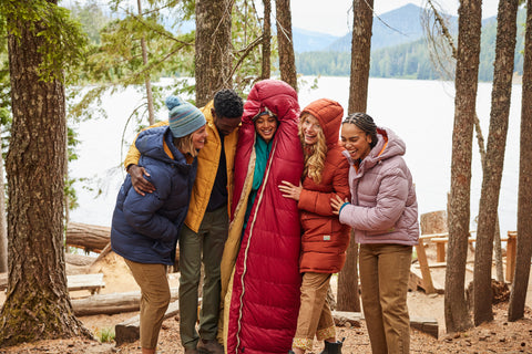 Group of friends by a lake wearing Toad&Co insulated outerwear made from 100% recycled materials