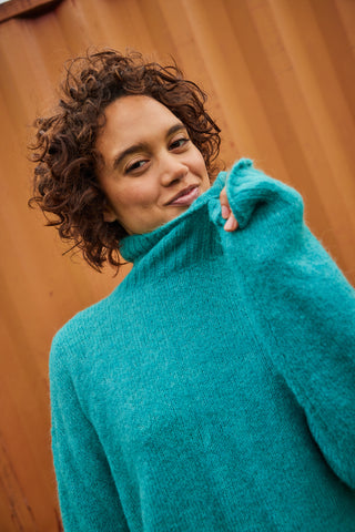 Female in a blue sustainable turtleneck sweater from Toad&Co
