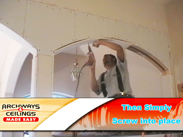 How to drywall an arch step 6 - a worker screwing drywall into the bottom side of a framed archway