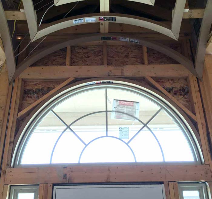 Fan-shaped arched window being framed above a front door under a groin vault