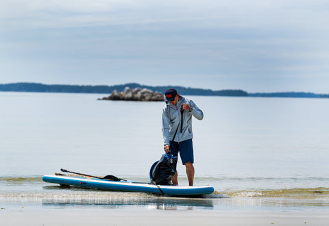 norm hann standing beside a sup at the shore