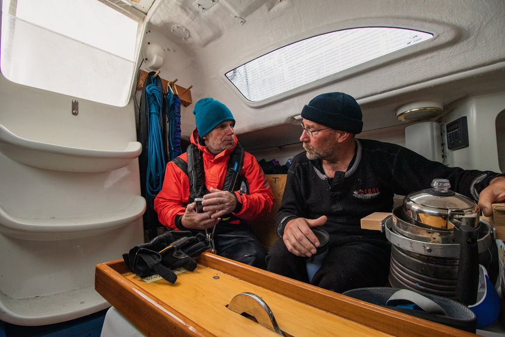 two men below deck of sail boat dicussing navigation