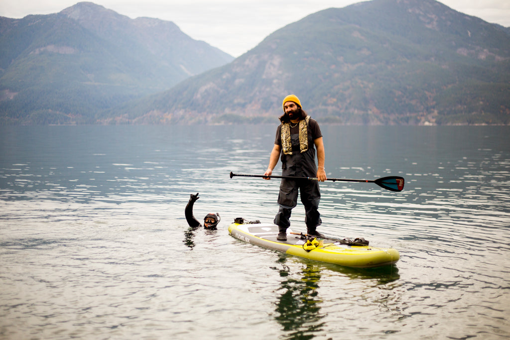 man fishing from a paddle board in how sound BC with diver next to him