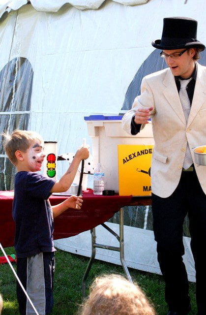 Alexander is performing a magic wand effect for a group of kids at a summer barbecue fundraiser