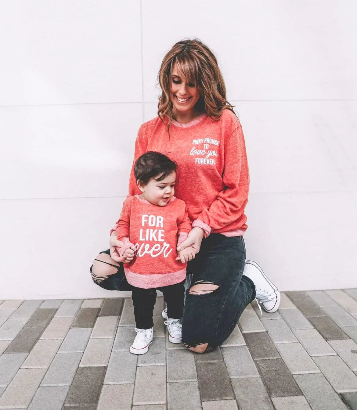 A mom and her toddler wearing matching red sweatshirts