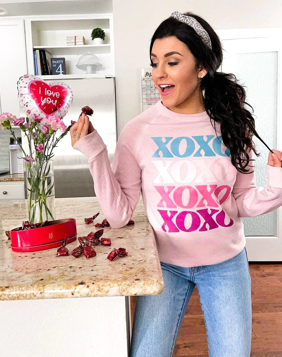 A woman wearing a pink sweatshirt that repeats XOXO