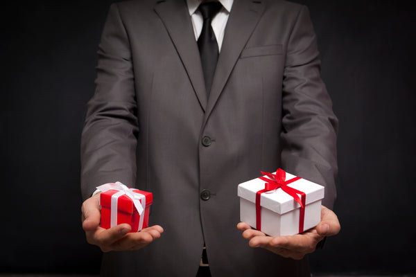 Man in a suit holding a gift in each hand.