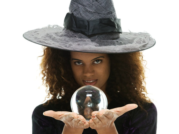 A pretty lady dressed as a witch holding a crystal ball.