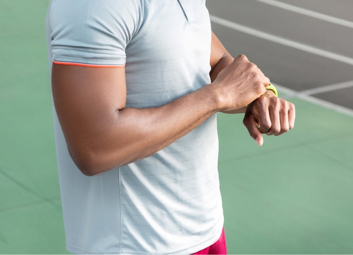 American Male Athlete Standing in Stadium Checking Fitbit Tracker