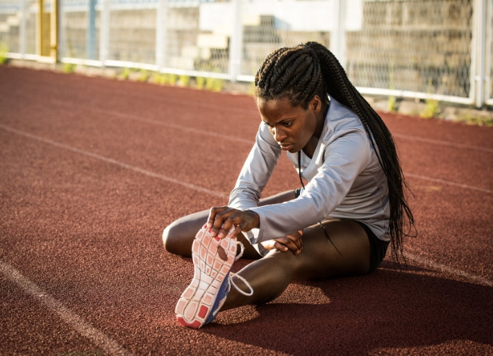 Young Female Track & Field Athlete Stretching