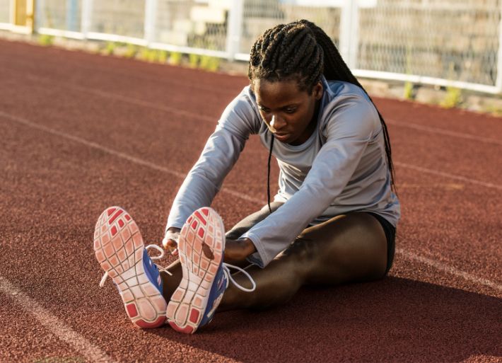 Female Athlete Stretching on Athletics Track