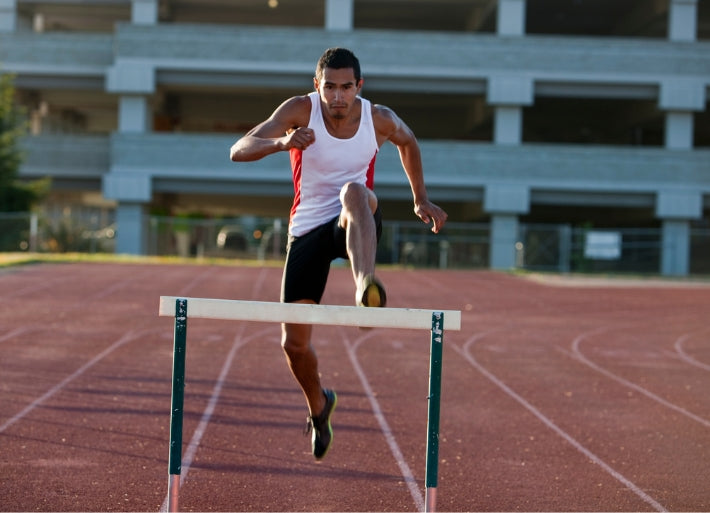 Young athlete jumping hurdles