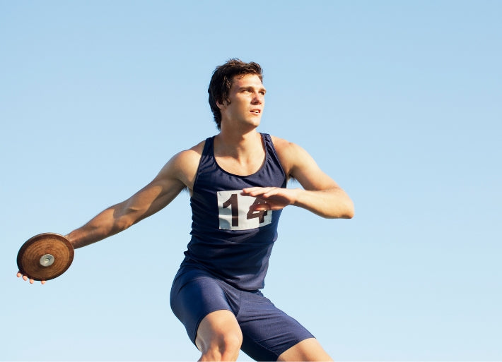 Young male athlete throwing discus