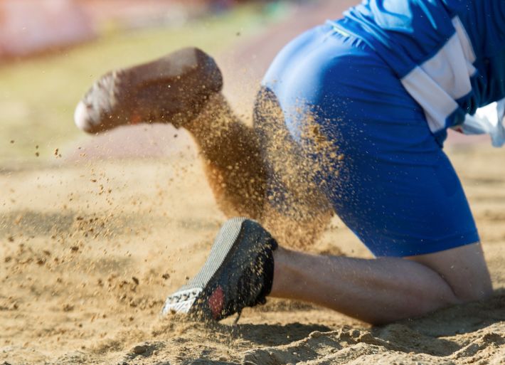 Young Male Athlete Jumping in Sandpit