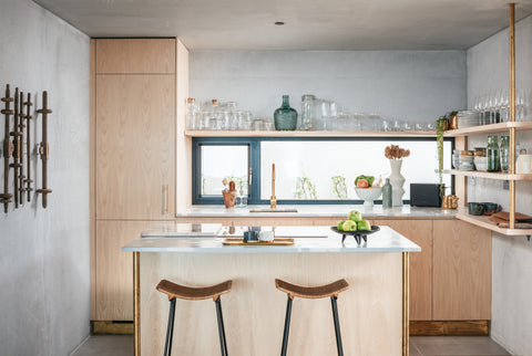Photograph of the inviting Ukiyo kitchen. Larch cladding and light woods are used alongside poured concrete, brass fittings and marble island.