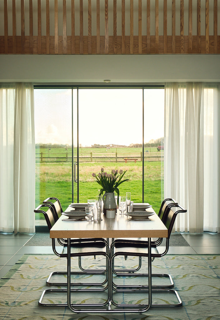 Dining room with table and chairs with view to garden. Living Architecture.