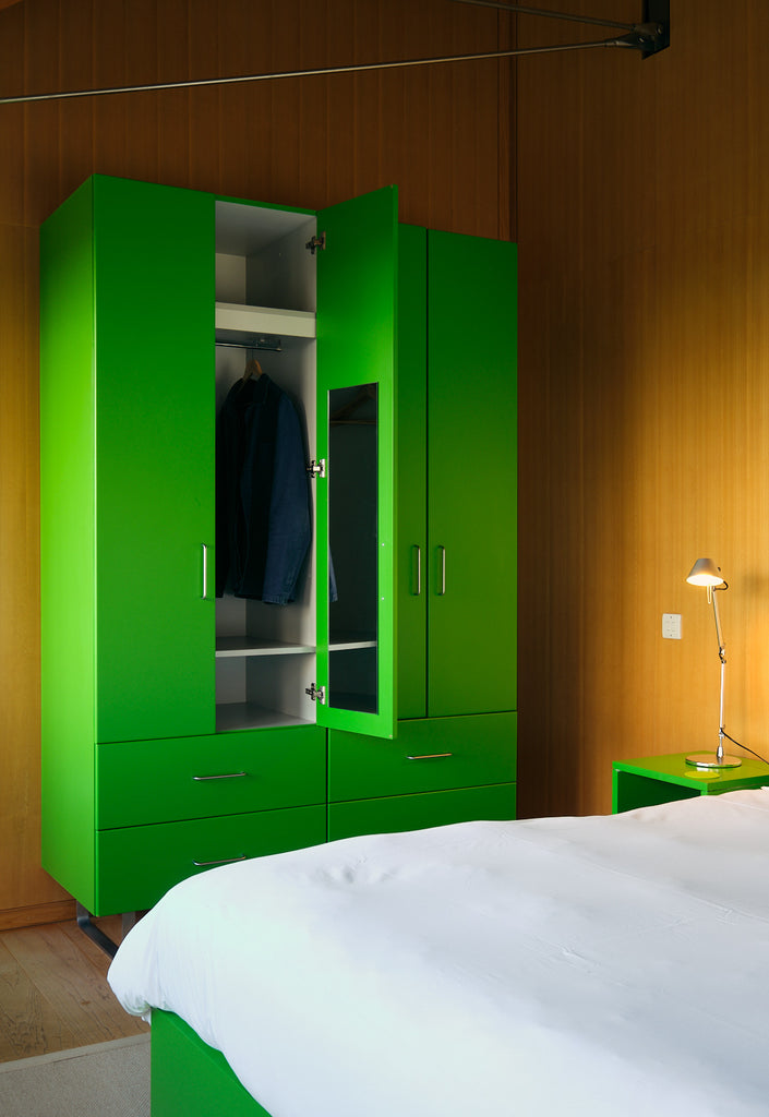 Bedroom, with cosy bed linen and modern bright green wardrobe. Living Architecture.