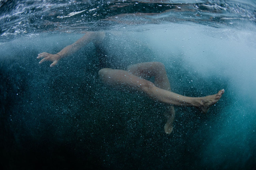 A swimmer plunged into aqua blue water – photograph by James Bowden