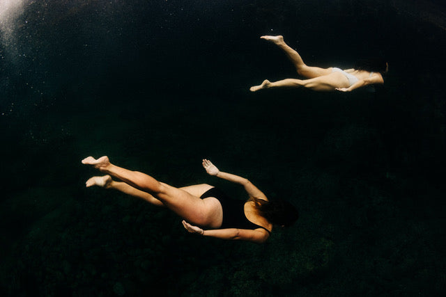 Underwater photograph of two swimmers diving deep down into the depths.