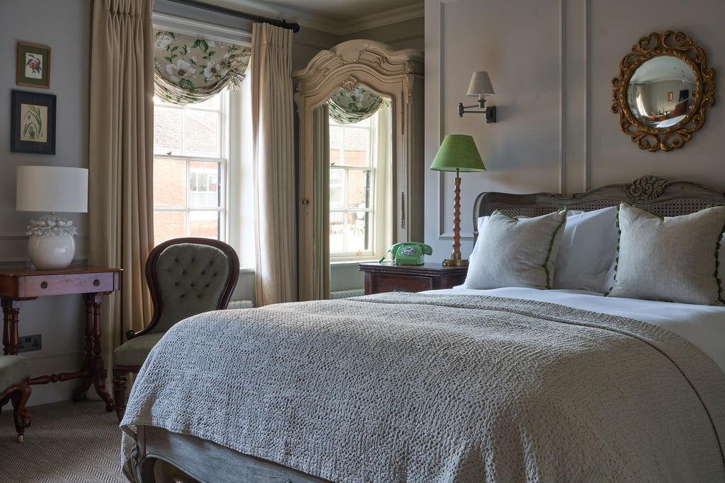 Bedroom with cosy bed, plush cushsions and edwardian features at Stanwell House Hotel.