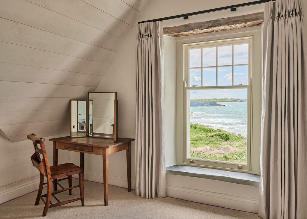 Wooden chair and mirror in bedoom overlooking the sea at Atlanta Trevone