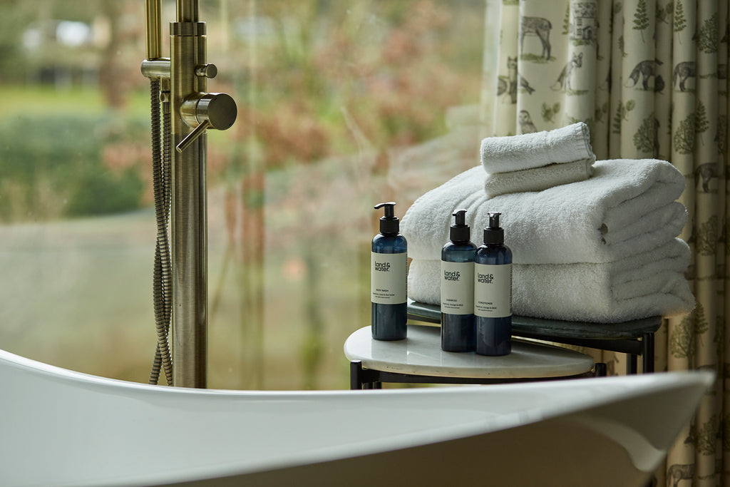 Photograph of land&water bath products by edge of bath.