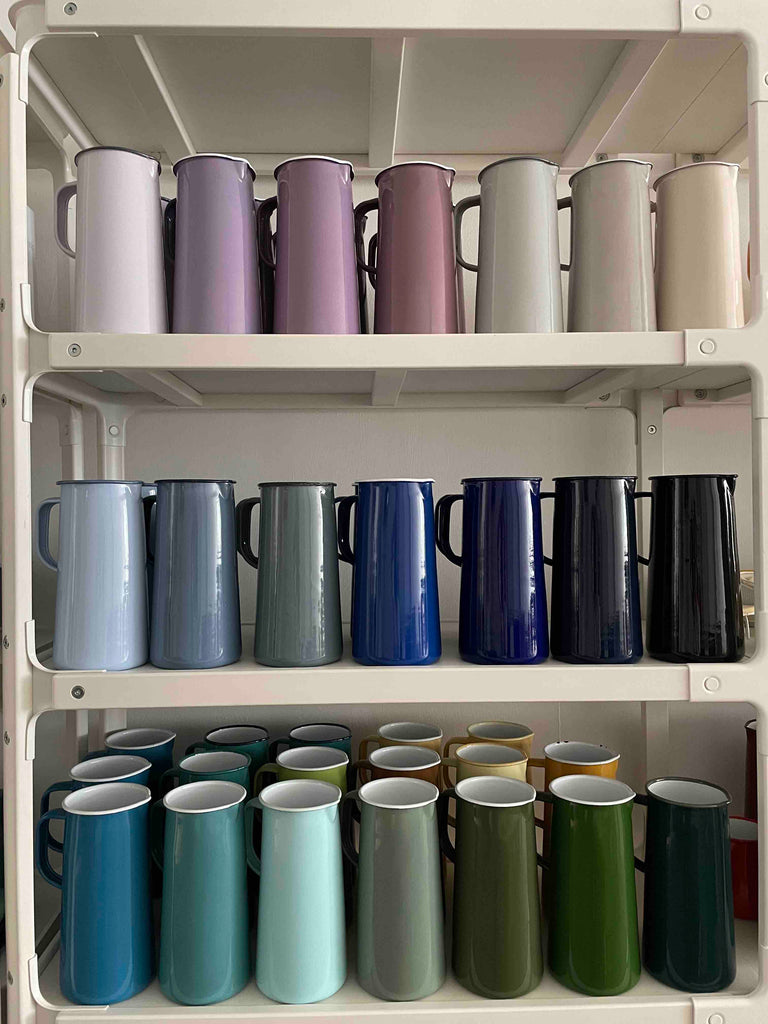 Three shelves of Falcon Enamelware 3-pint jug in variety of enamel colours.