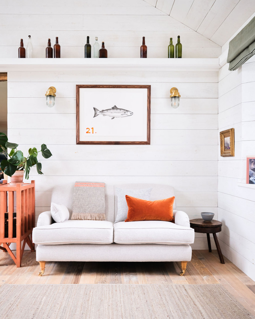 Plush sofa in the living room at Atlanta Trevone. Houseplants, colourful pictures on the walls and bottles on the mantelpiece contribute to the relaxing and light atmosphere.