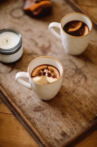 Two mugs of mulled wine with orange slices and cloves for decoration.