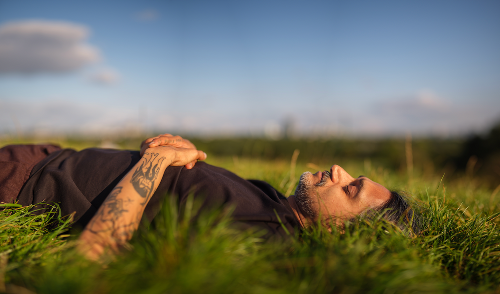 Man lying in grass catching sun rays.