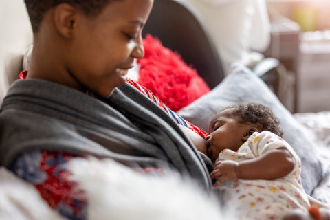 smiling Black mother breastfeeding baby