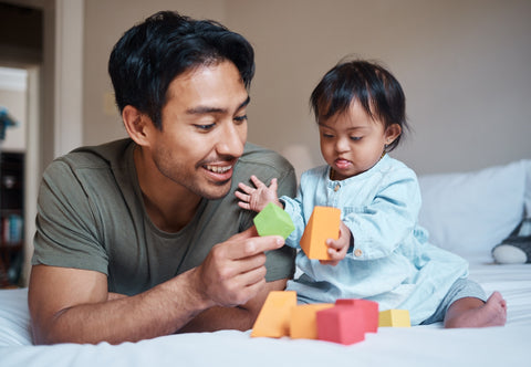 image of a dad with his disabled daughter, playing with blocks