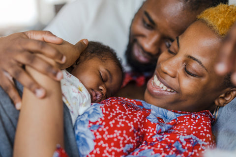 Black parents snuggling newborn baby in hospital